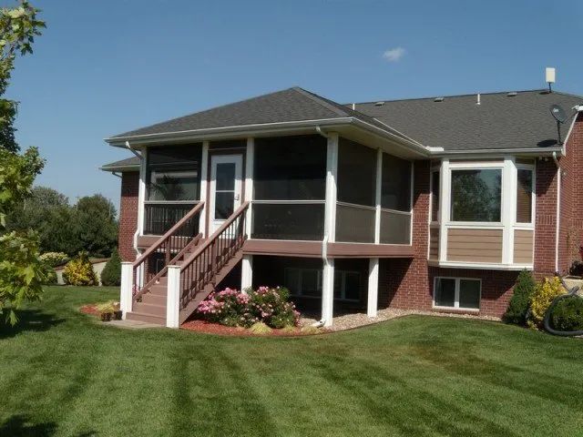 A brick house with a screened in porch and stairs