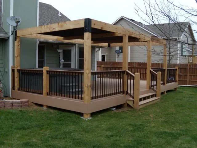 A wooden deck with a pergola in the backyard of a house