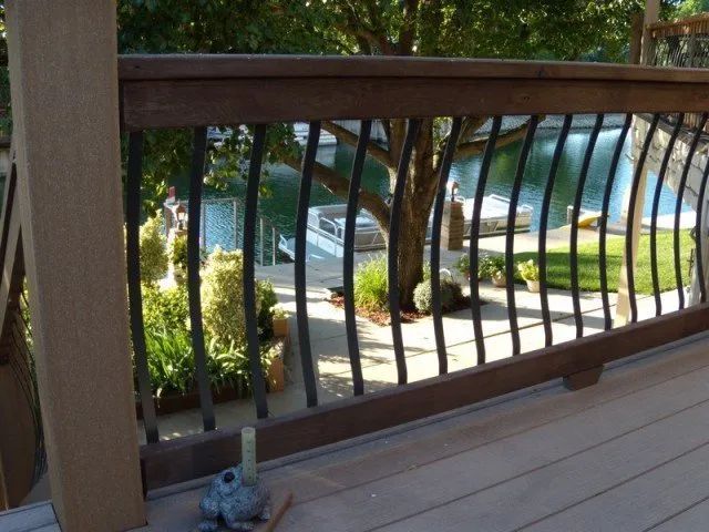A wooden deck with a metal railing overlooking a lake