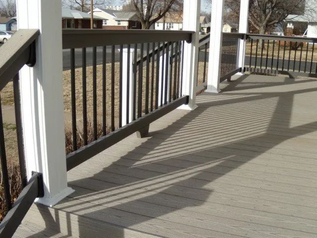 A deck with a black railing and white posts