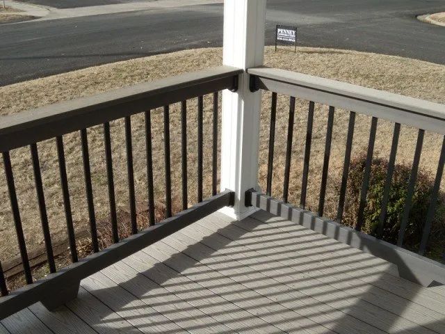 A balcony with a black railing and a white post