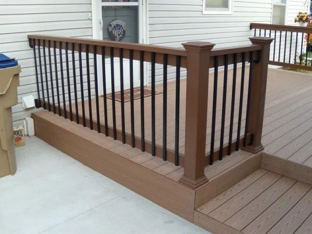 A wooden deck with a black railing and stairs