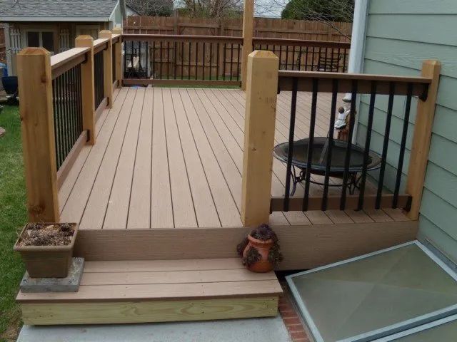 A wooden deck with a black railing and a fire pit