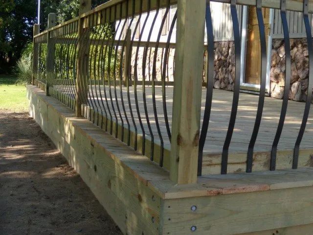 A wooden deck with a metal railing in front of a house