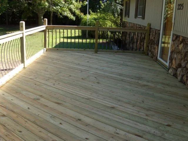 A large wooden deck with a railing in front of a house