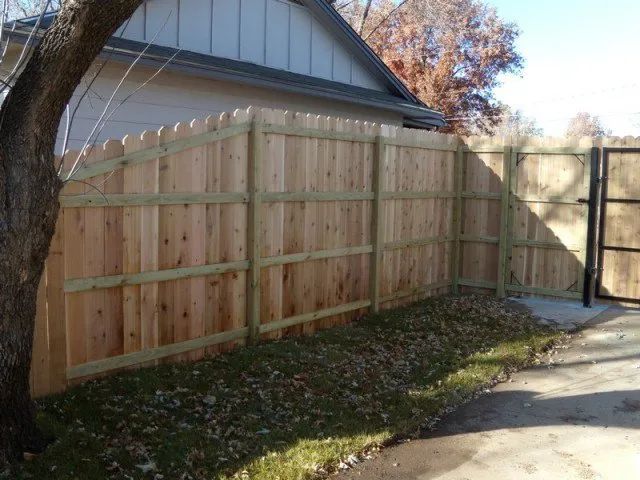 A wooden fence with a gate in front of a house