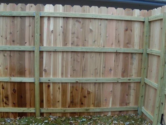 A wooden fence with a green frame is sitting in the grass