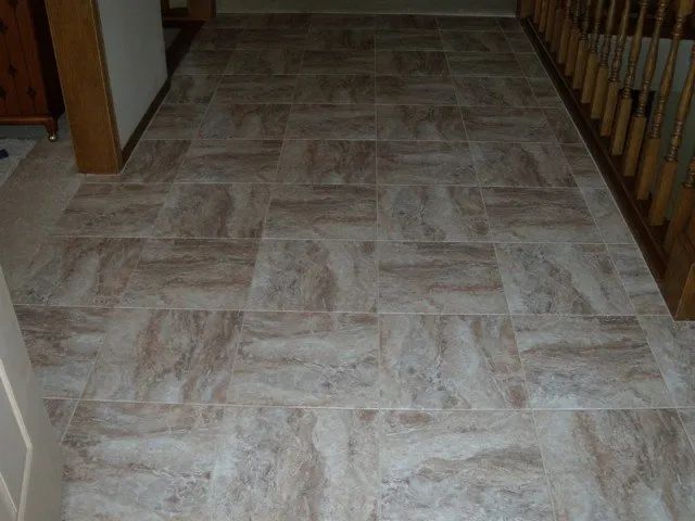 A hallway with tile floors and a wooden railing