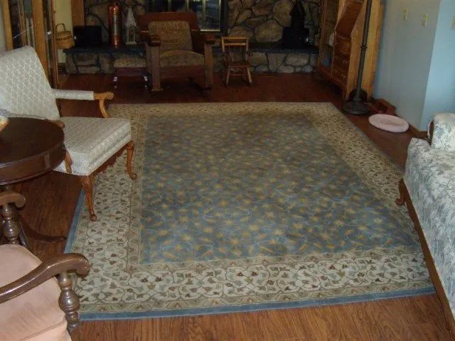 A living room with a rug and chairs and a fireplace