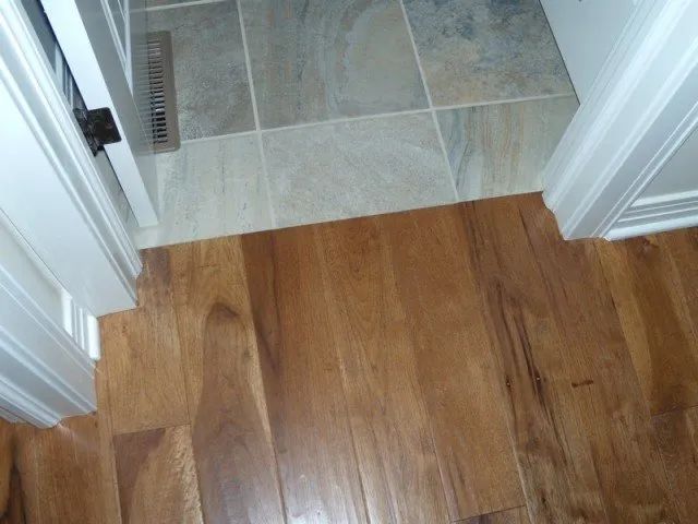 A wooden floor next to a tiled floor