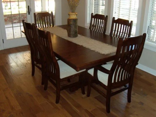 A dining room table with chairs and a vase on it
