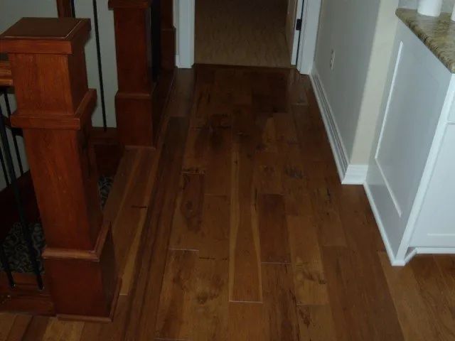 A hallway with hardwood floors and stairs in the background