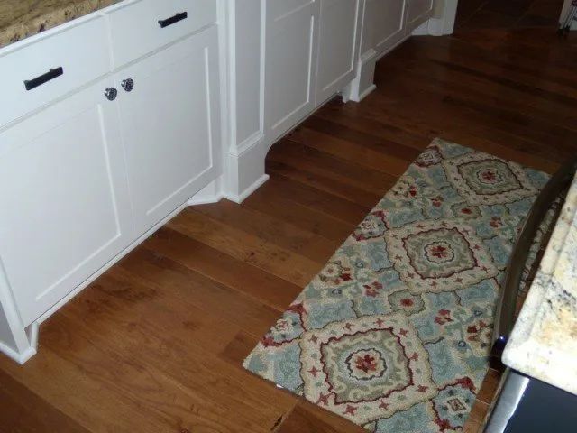 A kitchen with hardwood floors and a rug on the floor