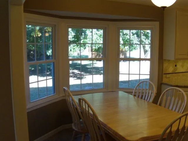 A dining room table and chairs in front of a bay window