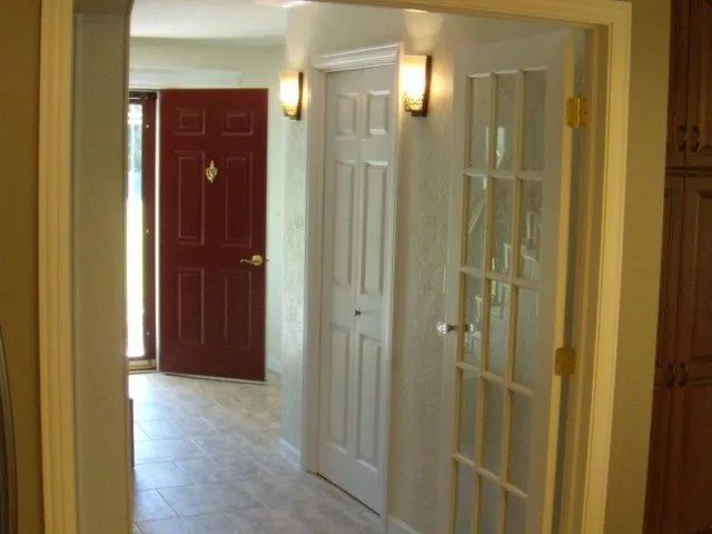 A hallway with white doors and a red door