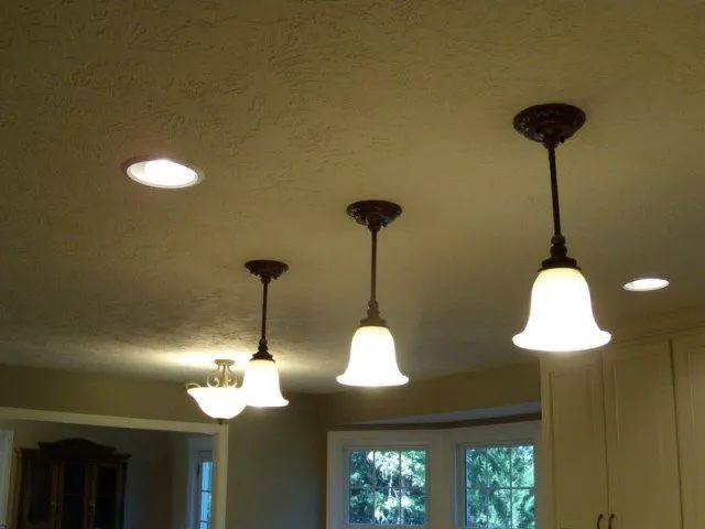 A kitchen with three lights hanging from the ceiling