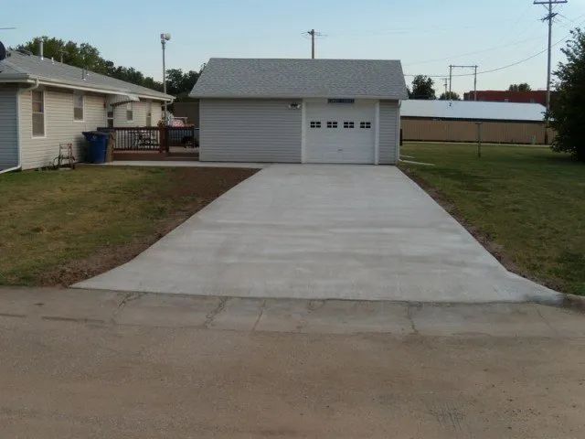 A concrete driveway leading to a garage and a house