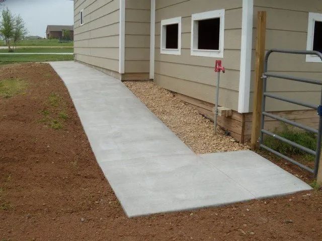A concrete walkway leading to a house with a gate