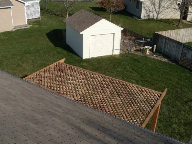 A white shed sits in the middle of a lush green yard