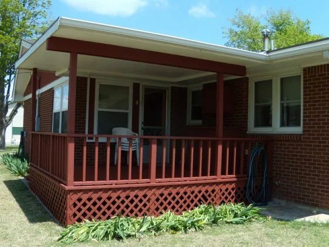 A brick house with a red porch and a white roof
