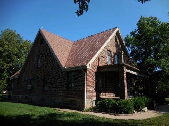 A brick house with a red roof and a porch