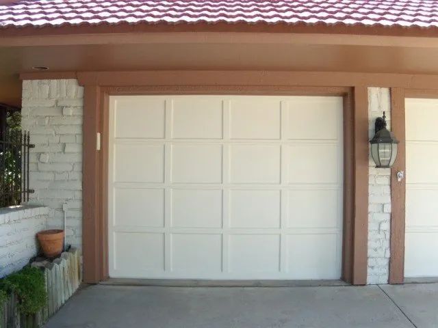 A white garage door with a red tile roof