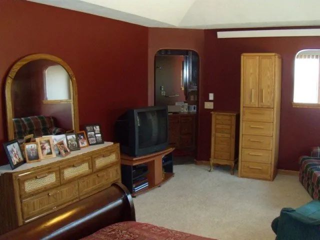 A bedroom with red walls and a dresser with pictures on it