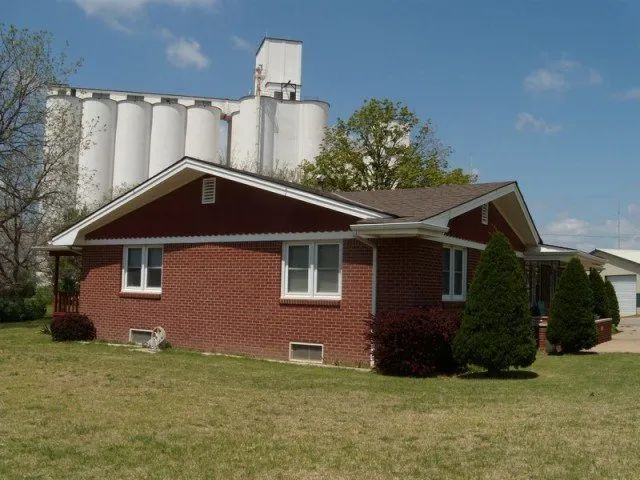 A red brick house with a white silo in the background