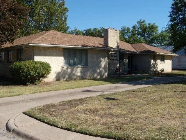 A white house with a brown roof and a chimney