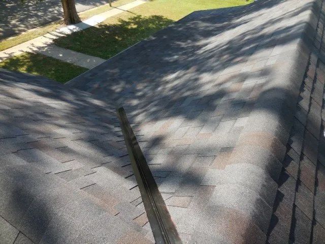 A roof with a lot of shingles on it and a tree in the background