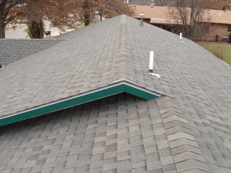 A large house with a gray roof and a driveway in front of it