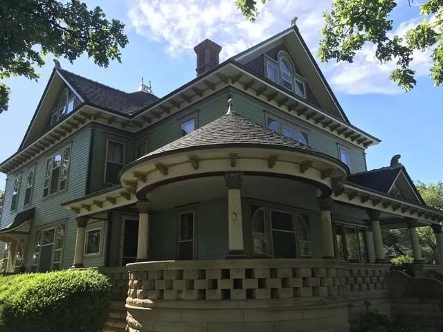 A large green house with a large porch