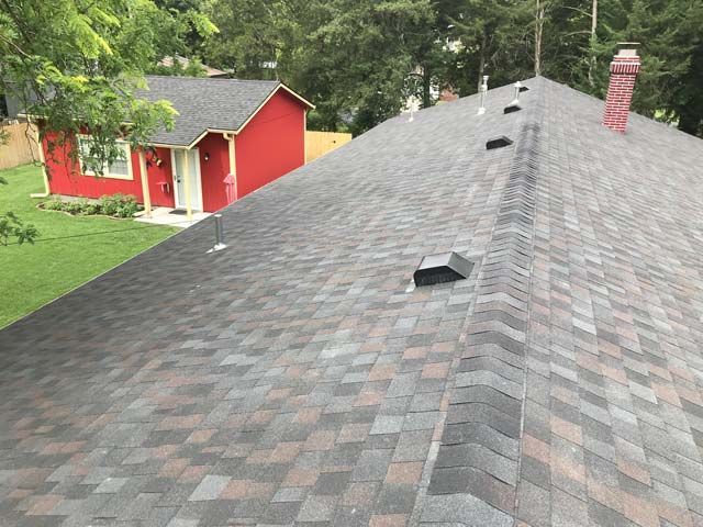 A roof of a house with a red house in the background