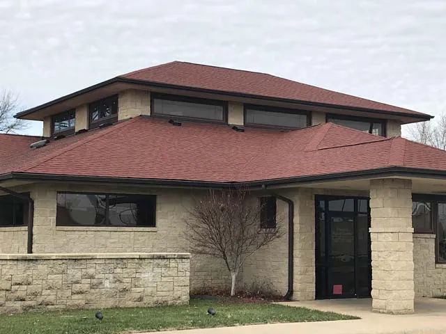 A large brick building with a red roof and a tree in front of it