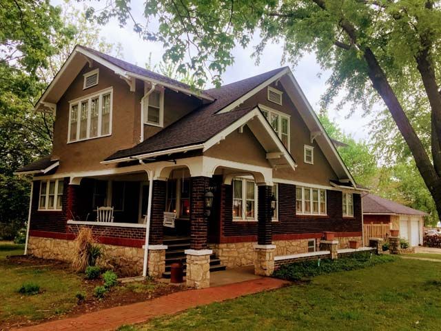 A large brown house with a porch and a lot of windows