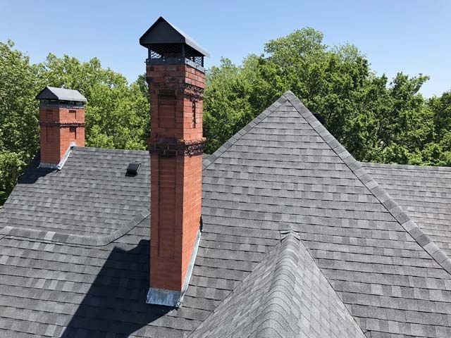 There are two chimneys on the roof of a house