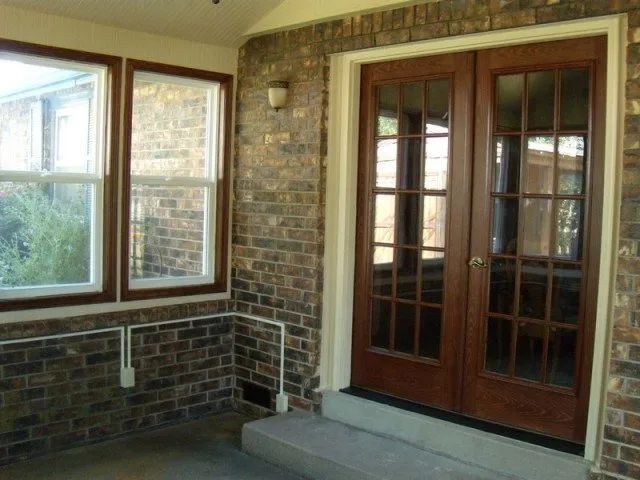 A screened in porch with brick walls and wooden doors