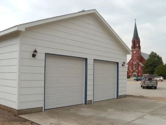 A white garage with a church in the background