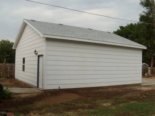 A white garage with a gray roof and a blue door