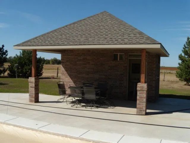 A small brick building with a table and chairs underneath it