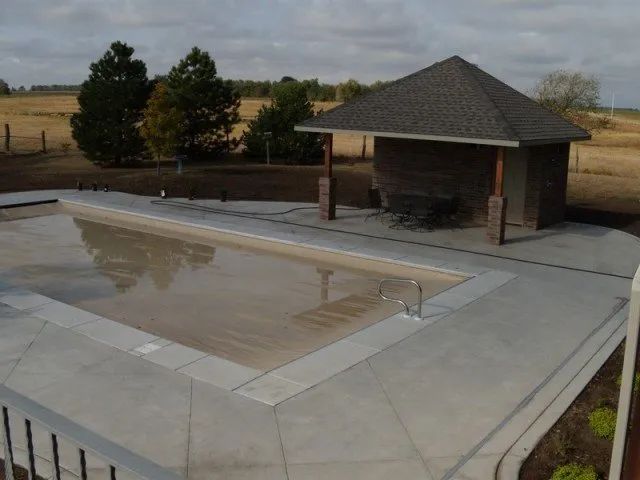 A large swimming pool with a gazebo in the background