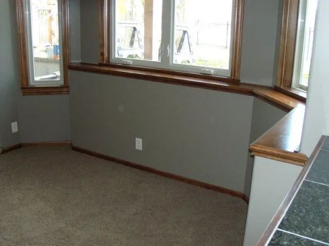 An empty room with two windows and a carpeted floor