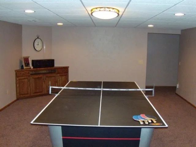 A ping pong table in a room with a clock on the wall