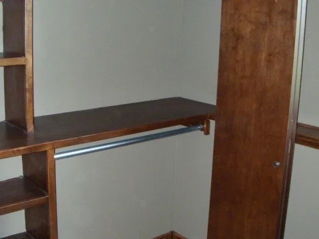 A walk in closet with wooden shelves and a mirror