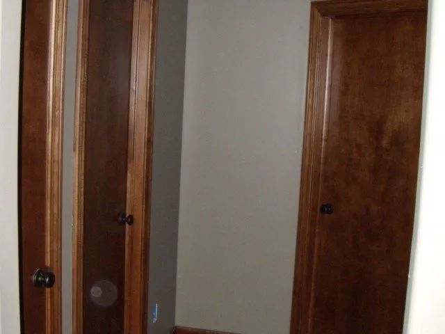 A hallway with two wooden doors and a mirror