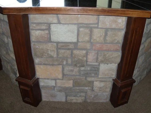 A stone fireplace with a wooden frame around it