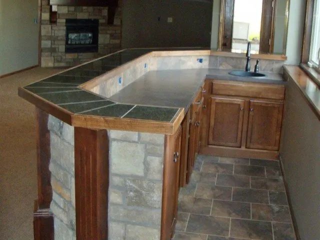 A kitchen with a stone counter top and wooden cabinets