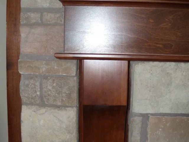 A fireplace with a wooden mantle and a stone wall