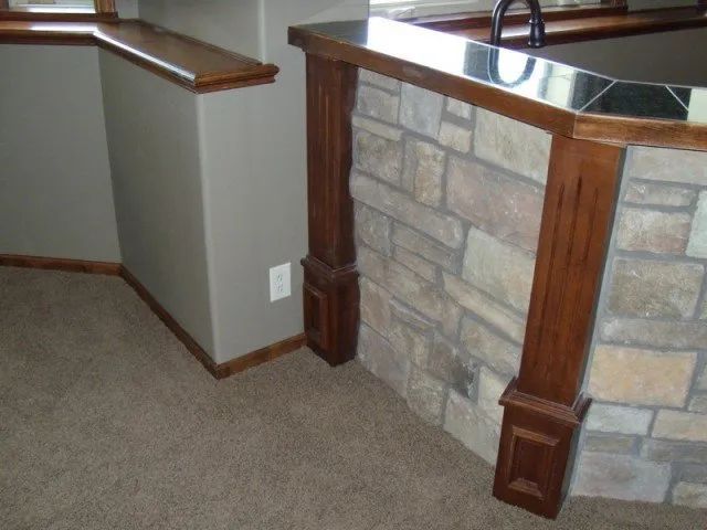 A kitchen with a stone wall and a wooden counter top