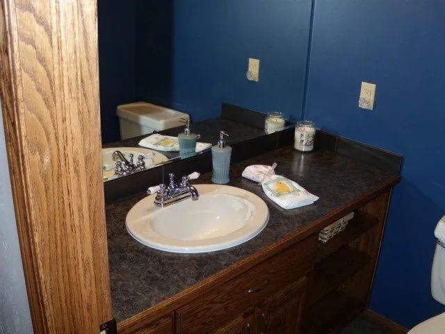 A bathroom with a sink a toilet and a mirror